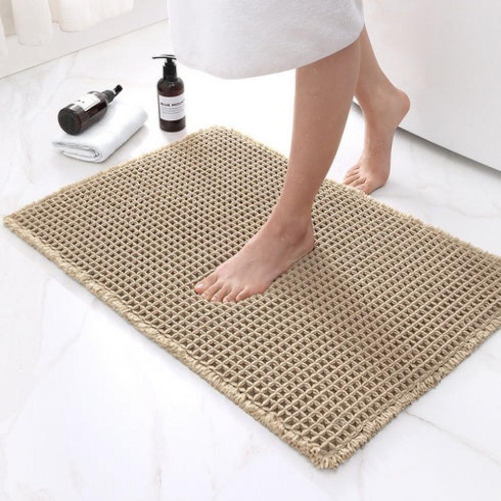 Person stepping onto a textured bath mat in a bathroom setting.
